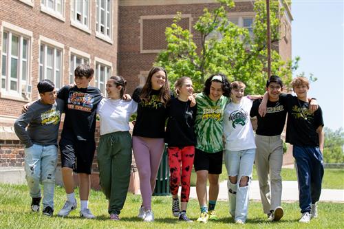 Students walking in front of school, smiling, sunny 